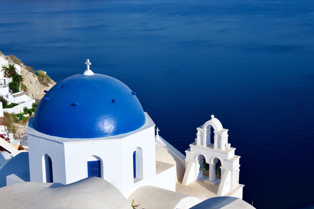 Kirche mit blauer Kuppel auf Santorini über der Ägäis