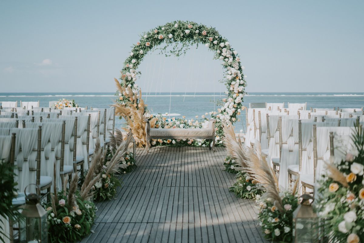 Blumenbogen für eine Trauung am Strand, dahinter das Meer
